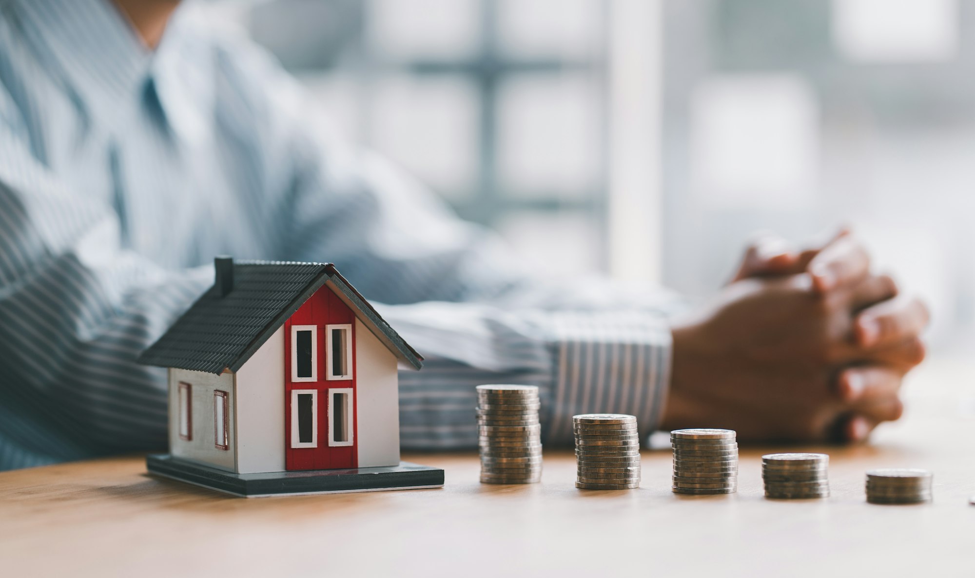 stack of money and home models, home insurance ideas and insurance agents for those interested.