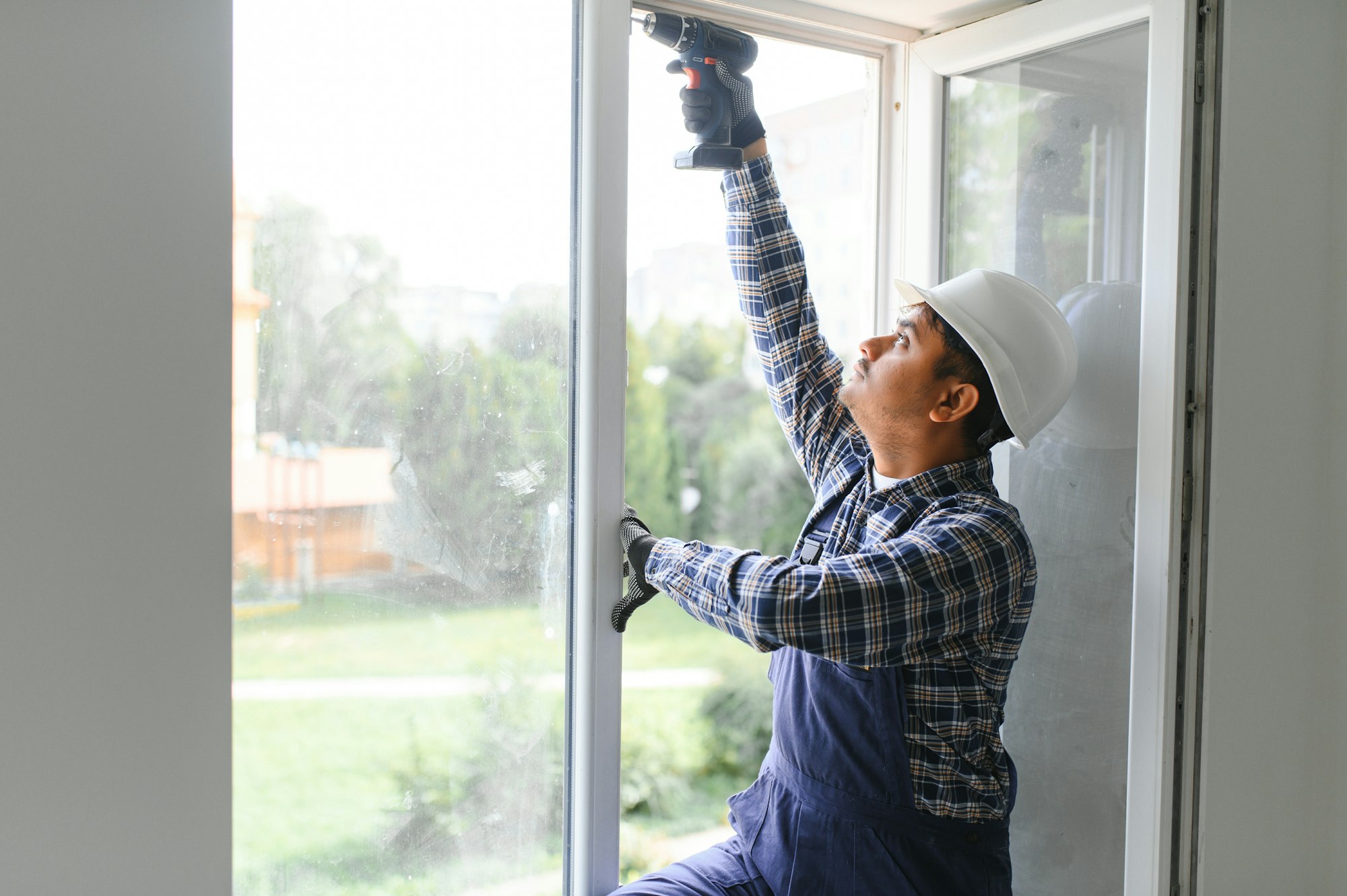 Indian service man installing window with screwdriver