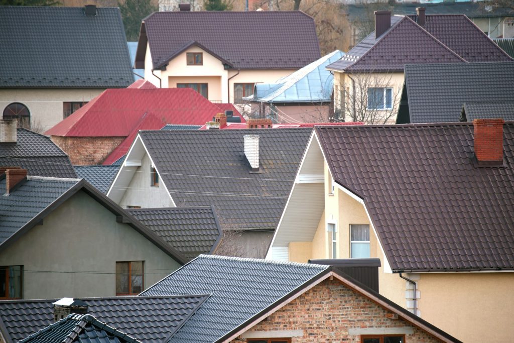 Residential houses with roof tops covered with metallic and ceramic shingles in rural suburban area
