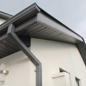 Close-up of new black gutters and downspouts installed on a modern white home in Loveland, CO